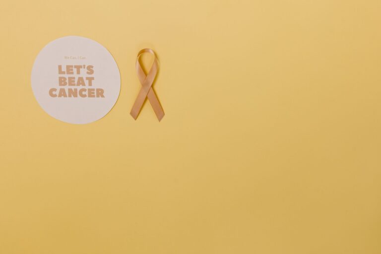 Minimalist design featuring a gold cancer awareness ribbon on yellow background.