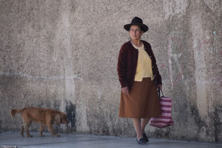 A local woman in traditional attire walks her dog in Huaraz, Peru, providing a glimpse into everyday life.