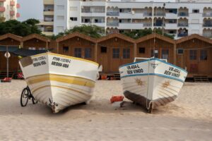 Colorful fishing boats resting on sandy Monte Gordo beach, Faro, Portugal.