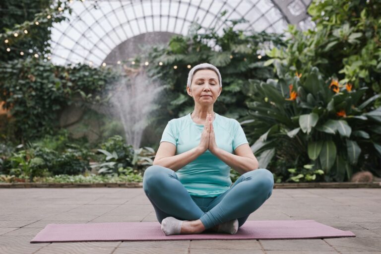 Elderly woman mediating in a tranquil botanical garden setting, embracing serenity and mindfulness.