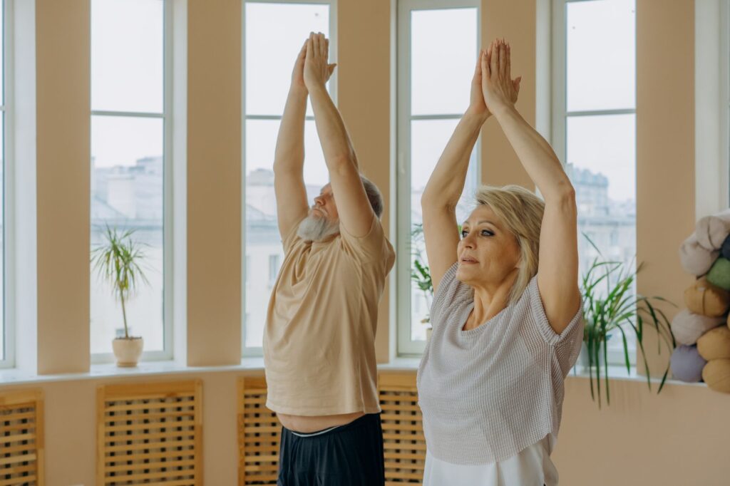 Senior couple practicing yoga poses indoors, promoting wellness and mindfulness.