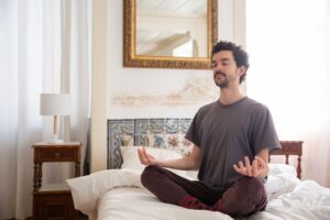 Discover tranquility as a man meditates in a serene bedroom environment, capturing the essence of peace.