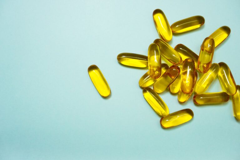 A collection of omega-3 capsules on a light blue surface, ideal for health and supplement themes.
