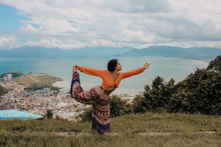 Woman in yoga pose overlooking the beautiful landscape of Paraty, Brazil, with sea and mountains.