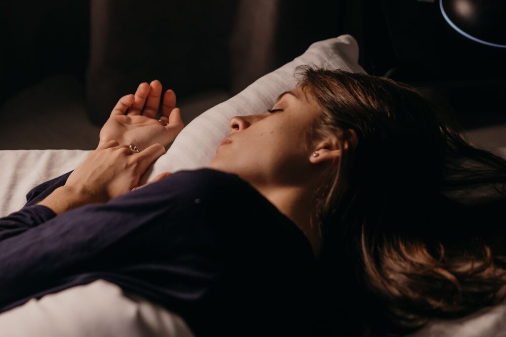A woman sleeping comfortably on a pillow in a softly lit bedroom, capturing a peaceful nighttime ambiance.