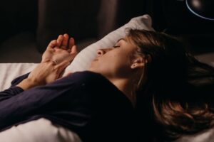 A woman sleeping comfortably on a pillow in a softly lit bedroom, capturing a peaceful nighttime ambiance.